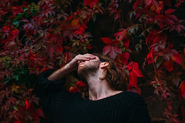 Man next to a tree with his hand on his face