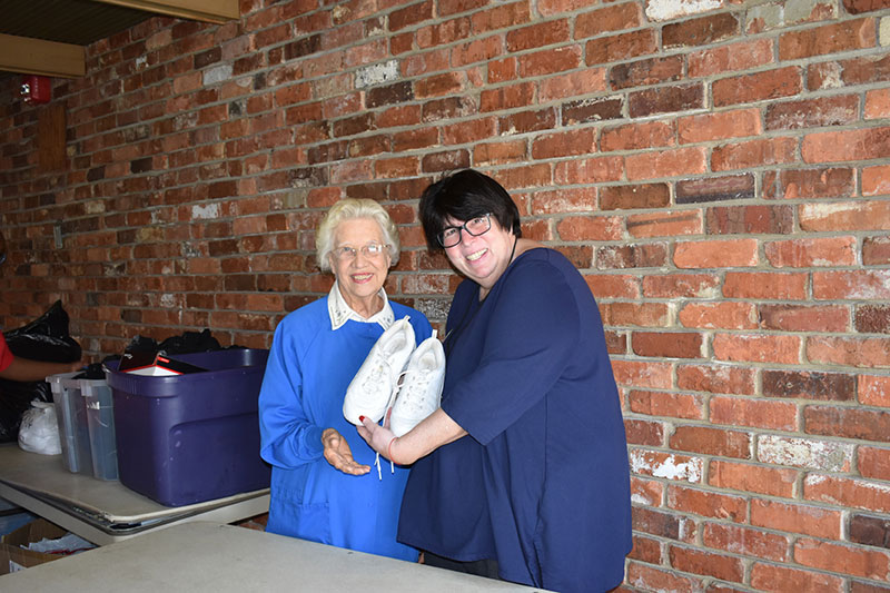 Woman giving shoes to anothe woman