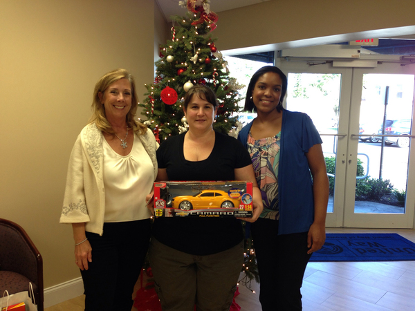 Nancy Vaniman, Commander U.S. Navy (Retired), Director of MISSION UNITED, (left) presented holiday gifts to the Gibson Family